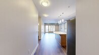 Located on Butler Street in Pittsburgh's vibrant Lawrenceville neighborhood, this 2-bedroom, 2-bathroom unit offers a thoughtfully designed layout with modern industrial-style finishes throughout. Rich hardwood flooring runs continuously across the entire floor plan, anchoring a cohesive and contemporary aesthetic.

The open-concept kitchen is a standout feature, showcasing sleek white cabinetry, white quartz countertops, a textured tile backsplash, stainless steel appliances including a gas range, microwave, and French-door refrigerator, and a curved kitchen island with pendant lighting overhead. Exposed metal ductwork runs along the ceiling, adding an urban loft character to the space.

The living area is bright and airy, with large windows and glass doors that invite abundant natural light and offer views of the surrounding streetscape. The exposed ductwork continues here, reinforcing the industrial design theme.

The primary bedroom is generously sized, with neutral walls and a walk-in closet outfitted with wire shelving and hanging rods. The second bedroom is a comfortable, well-proportioned room with the same consistent hardwood floors and neutral palette. Both bathrooms feature clean, white tub-shower combinations, white vanities with quartz countertops, and wood flooring, maintaining the unit's modern, cohesive style throughout.