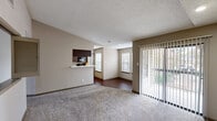 Located at 3725 William Dehaes Dr in Irving, Texas, this single-floor residence offers a well-planned layout with a comfortable and functional design throughout. The living area is generously sized, featuring plush carpeting, a textured ceiling, and a tile-surround wood-burning fireplace that serves as a focal point. A large sliding glass door with vertical blinds opens to a private balcony, filling the space with natural light and providing outdoor views. An interior pass-through window connects the living area to the kitchen, enhancing the open feel of the floor plan. The galley-style kitchen is efficiently designed with dark espresso cabinetry, tile backsplash, light countertops, a stainless steel sink, and black appliances including a refrigerator and microwave. A dedicated laundry area with washer and dryer hookups is conveniently situated within the kitchen corridor. Wood-look flooring runs through the kitchen and dining areas, while carpet covers the living and bedroom spaces. The bedroom features a ceiling fan, direct access to a private bathroom, and a spacious walk-in closet equipped with wire shelving for ample storage. Neutral warm-toned walls and consistent finishes throughout give the space a cohesive and move-in-ready appearance.