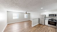Located in Lexington, KY 40517, this single-floor 2-bedroom, 1-bathroom home offers a clean, modern aesthetic with thoughtful updates throughout. The open living area features warm wood-look vinyl flooring, neutral gray walls, and a textured ceiling with a ceiling fan, creating a comfortable and airy atmosphere. Multiple windows allow natural light to fill the space, enhancing the bright, welcoming feel.

The kitchen is a standout feature, showcasing white shaker-style cabinetry, granite countertops, a classic subway tile backsplash, and a full suite of stainless steel appliances including a refrigerator, range with microwave, and dishwasher. A peninsula counter connects the kitchen to the living area, providing additional prep space and an open sightline.

Both bedrooms are comfortably sized with the same wood-look flooring, neutral tones, and windows fitted with blinds. One bedroom includes a double sliding-door closet for added storage convenience. Ceiling fans are present in multiple rooms for year-round comfort.

The bathroom features a white vanity with brushed nickel fixtures, a well-lit mirror, and convenient in-unit stacked washer and dryer hookups, adding a practical laundry solution within the home. The consistent finishes and updated features throughout make this a move-in ready residence.
