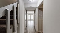 This two-story, 3-bedroom, 2-bathroom home offers a well-organized layout spread evenly across both floors, connected by a staircase. The main level features light-toned wood-look flooring throughout, beginning with an entry hallway lined with closet storage that leads toward a bright living area with French doors and abundant natural light. The galley-style kitchen is efficiently designed with dark espresso cabinetry, granite countertops, white subway tile backsplash, black and stainless steel appliances, and a stacked in-unit washer and dryer conveniently integrated into the layout. A separate living area on this floor includes a ceiling fan, large windows, and access to an exterior door. Upstairs, the three bedrooms are finished with plush carpet and neutral tones. The generously sized primary bedroom features direct access to an en-suite bathroom equipped with a dark-framed vanity mirror, granite countertop, and undermount sink. A second full bathroom includes a soaking tub with shower. Additional hallway space and closets on the upper level provide practical storage. Throughout the home, consistent neutral wall colors, textured ceilings, and wood-look flooring on the main level create a cohesive and functional living environment.