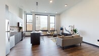 This single-floor residence at 200 Euclid Avenue sits in the heart of downtown Cleveland, offering a well-designed open-concept layout with contemporary finishes and striking views of the city skyline. The living area features warm hardwood-style flooring, clean white walls, and large black-framed windows that frame panoramic views of Cleveland's iconic buildings, flooding the space with natural light.

The kitchen is a standout feature, outfitted with wood-toned upper cabinetry, slate-gray lower cabinets, a bold geometric tile backsplash, stainless steel appliances, and a spacious island with a quartz countertop and bar seating. The open layout allows the kitchen to flow seamlessly into the living and dining areas.

The bedrooms are calm and understated, with neutral walls, hardwood-style flooring, and thoughtful lighting. Two bathrooms continue the modern aesthetic: one features a glass-enclosed walk-in shower with white subway tile and hexagonal floor tile with matte black fixtures, while the second includes a full soaking tub, wood vanity, and matching tile detailing. The overall ambiance throughout is contemporary urban living with a warm, cohesive design sensibility.