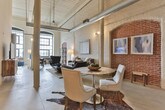 Located in Columbus, Georgia, this single-floor loft showcases the timeless appeal of industrial architecture thoughtfully converted into a contemporary living space. The open-concept layout is anchored by whitewashed exposed brick walls, original structural columns, and soaring ceilings that lend the space an expansive, airy quality. Polished concrete floors flow throughout, tying together each area with a cohesive, minimalist aesthetic.

The living area is a standout, featuring a dramatic arched brick alcove that serves as a focal point alongside exposed pipes and ductwork that honor the building's industrial heritage. The kitchen is well-appointed with light maple cabinetry, dark granite-style countertops, and a full suite of black appliances including a range, dishwasher, microwave, and refrigerator, all beneath tall ceilings with track lighting.

The bedroom offers a more intimate atmosphere with smooth walls and warm, subdued lighting, providing a calm retreat from the open communal spaces. Two full bathrooms serve the residence, each featuring light wood vanity cabinetry and clean, functional finishes. One includes a shower-tub combination, while the other offers a vanity with ample counter space. The overall ambiance of the space balances raw, historic character with comfortable, modern livability.