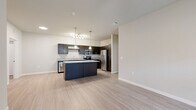 This well-appointed 2-bedroom, 2-bathroom residence offers a thoughtfully designed single-floor layout that maximizes comfort and functionality. The open-concept living and kitchen area serves as the heart of the home, featuring light wood-look flooring that flows seamlessly throughout. The kitchen stands out with dark espresso cabinetry, granite countertops, a large center island with pendant lighting, and a full suite of stainless steel appliances, including a refrigerator, range, microwave, and dishwasher. A track light fixture adds additional illumination over the workspace.

The living room is bright and airy, benefiting from natural light through large windows fitted with white blinds, and is accented by a ceiling fan overhead. Both bedrooms are carpeted for comfort and share a similarly warm, neutral palette, each receiving natural light through sizable windows. The two full bathrooms mirror each other in design, featuring dark vanity cabinetry with granite countertops, tub-shower combinations, and light wood-look tile flooring. A dedicated laundry room with washer and dryer hookups provides added convenience. Two closets offer ample storage throughout the residence.
