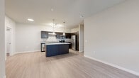 This well-appointed 2-bedroom, 2-bathroom residence offers a thoughtfully designed single-floor layout that maximizes comfort and functionality. The open-concept living and kitchen area serves as the heart of the home, featuring light wood-look flooring that flows seamlessly throughout. The kitchen stands out with dark espresso cabinetry, granite countertops, a large center island with pendant lighting, and a full suite of stainless steel appliances, including a refrigerator, range, microwave, and dishwasher. A track light fixture adds additional illumination over the workspace.

The living room is bright and airy, benefiting from natural light through large windows fitted with white blinds, and is accented by a ceiling fan overhead. Both bedrooms are carpeted for comfort and share a similarly warm, neutral palette, each receiving natural light through sizable windows. The two full bathrooms mirror each other in design, featuring dark vanity cabinetry with granite countertops, tub-shower combinations, and light wood-look tile flooring. A dedicated laundry room with washer and dryer hookups provides added convenience. Two closets offer ample storage throughout the residence.