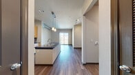 Located at 4400 W Spruce St in Tampa, FL, this 1-bedroom, 1-bathroom residence offers a thoughtfully designed single-floor layout that maximizes functionality and comfort. The open-concept living and kitchen area is anchored by a sleek kitchen island with a dark countertop and built-in sink, illuminated by stylish pendant lighting. The kitchen features warm wood-toned cabinetry, a tile backsplash, and a full suite of stainless steel appliances including a refrigerator, electric range, and microwave. Rich hardwood-style flooring flows throughout the main living areas, while a sliding glass door at the end of the living space invites natural light and provides access to an outdoor balcony. The spacious bedroom is finished with soft carpeting, a ceiling fan, and a window with exterior views. A walk-in closet with wire shelving provides ample storage. The bathroom includes a tiled tub/shower combination, wood-toned vanity cabinetry, and tile flooring. An adjacent closet houses an in-unit washer, adding everyday convenience. A built-in desk with overhead cabinetry in the hallway area offers a practical workspace. Textured ceilings and neutral wall tones complete the clean, modern aesthetic throughout.