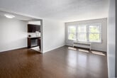 This 2-bedroom, 1-bathroom unit at 939B Western Road in London, Ontario offers a thoughtfully arranged single-floor layout. The open living area is a standout feature, anchored by a large triple-pane window that floods the space with natural light and provides views of the tree-lined neighbourhood. Hardwood-style flooring runs throughout the living and bedroom areas, complemented by neutral white walls and a textured ceiling. A baseboard radiator beneath the main window provides consistent heating.

The galley-style kitchen is positioned adjacent to the living area and features dark espresso cabinetry, stainless steel appliances including a dishwasher, stove, and microwave, as well as a tiled backsplash and light tile flooring. A window at the end of the kitchen adds additional natural light.

Both bedrooms are bright and modestly sized, each featuring hardwood-style flooring, large windows with garden views, and baseboard heating units. The primary bedroom offers a comfortable footprint suitable for standard bedroom furniture.

The bathroom is finished in light neutral tile, featuring a vanity with storage, an overhead cabinet with mirror, and a tiled shower surround, maintaining a clean and functional aesthetic throughout.