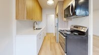 Located at 1 Marquette in Toronto's York neighbourhood, this thoughtfully renovated one-bedroom, one-bathroom unit offers a clean, modern aesthetic throughout. Light hardwood flooring flows seamlessly across every room, creating a warm and cohesive feel. The open entrance leads into a combined living and dining area filled with natural light from a wide bank of windows, complemented by recessed pot lighting and baseboard heating. The galley-style kitchen is efficiently designed with warm wood cabinetry, brass hardware, white quartz countertops, a stainless steel sink, and full appliances including an electric range, refrigerator, and over-the-range microwave. The bedroom is a comfortable, well-proportioned retreat featuring a large mirrored sliding closet, a radiator, and a window with a leafy outdoor view. Two closets provide ample storage throughout the unit. The bathroom is elegantly finished with marble-effect wall tiles surrounding the soaker tub and shower, a wood vanity with brass fixtures, and large-format floor tiles. A private balcony extends the living space outdoors, offering views of the surrounding neighbourhood and mature trees. The unit also includes a dedicated hallway connecting the main spaces efficiently.