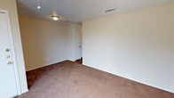 This single-floor space offers a straightforward and functional layout designed for comfortable everyday living. The interior is characterized by neutral, light-toned walls that create a clean and open atmosphere, complemented by wall-to-wall carpeting in a warm beige hue that adds a soft, cozy feel underfoot. The textured popcorn ceiling adds a classic touch to the space, while flush-mount ceiling light fixtures provide consistent overhead illumination throughout. Ventilation is supported by ceiling-mounted HVAC vents, ensuring a comfortable interior climate year-round. The room features standard interior doors with clean white trim and frames, contributing to the cohesive, understated aesthetic. Electrical outlets are conveniently positioned along the baseboards, offering practical accessibility across the room. The overall ambiance is calm and neutral, providing a blank canvas that can be easily adapted to a variety of uses and personal styles. The space is well-maintained and move-in ready, making it a versatile option for those seeking a practical and unassuming environment.