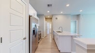 This single-story, 2-bedroom, 1-bathroom residence offers a clean, modern aesthetic with functional design throughout. The open-concept kitchen and living area serves as the heart of the home, featuring light hardwood-style flooring, recessed lighting, and a ceiling fan that enhances airflow and comfort. The kitchen is well-equipped with stainless steel appliances — including a refrigerator with ice maker, electric range, and microwave — complemented by crisp white cabinetry, a granite-topped island with an undermount sink, and a classic subway tile backsplash. The living area flows naturally from the kitchen, with natural light entering through windows fitted with blinds and access to an exterior door.

Both bedrooms feature plush carpeting and ceiling fans, providing a comfortable retreat. The primary bedroom is a well-proportioned space with direct access to the shared bathroom, and includes a dedicated walk-in closet with built-in shelving and hanging rods. The secondary bedroom offers dual windows that bring in ample natural light. The full bathroom is finished with a granite-topped vanity, wood-style flooring, and a shower-tub combination. A hallway connects the private areas of the home, and a staircase is also present within the layout.