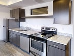 Located at 728 Market St in the heart of downtown Chattanooga, Tennessee, this modern single-floor unit offers a thoughtfully designed open layout with contemporary finishes throughout. The living area is bathed in natural light through large sliding glass doors that open to a private balcony, offering striking views of the Chattanooga skyline and surrounding urban landmarks. Light-toned hardwood-style flooring runs through the main living spaces, complementing the clean white walls and recessed lighting.

The kitchen is well-appointed with stainless steel appliances, including a range, dishwasher, and refrigerator, alongside granite-style countertops and dark espresso cabinetry that provides generous storage. Upper cabinets and a pass-through window detail add both functionality and visual interest to the kitchen area.

The bedroom features plush carpeting, clean white walls, and a spacious walk-in closet with built-in shelving, offering ample storage. A louvered closet door in the adjacent hallway provides additional storage access.

The bathroom is finished in a clean, modern aesthetic with white subway tile in the tub/shower surround, grey floor tile, dark wood vanity cabinetry, granite countertops, and recessed lighting — creating a sleek and functional space. Overall, the unit presents a cohesive modern design ideal for urban living.