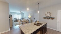 This single-floor residence on Bridgewater Drive in Clarksville, Tennessee, offers a thoughtfully designed open-concept layout that seamlessly connects the kitchen, dining area, and living room. The kitchen is a standout feature, showcasing dark cabinetry, granite countertops, stainless steel appliances, a large center island with pendant lighting and bar seating, and a dedicated pantry for ample storage. The adjacent dining area provides a welcoming space for gatherings, while the living room benefits from natural light streaming through large windows and a ceiling fan overhead. A comfortable sitting nook near the entryway adds an additional retreat space with views to the outside. The bedrooms are carpeted and generously sized, each with ceiling fans and large windows. The primary bedroom includes a spacious walk-in closet outfitted with extensive wire shelving on all sides. The bathroom features dark cabinetry, a granite vanity, a large mirror, and a full tub-shower combination. Wood-look flooring runs throughout the main living areas, complementing the neutral color palette that creates a cohesive and inviting ambiance. A dedicated laundry room with full-size washer and dryer connections rounds out the practical amenities of this well-equipped home.