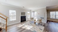 This two-story residence offers a thoughtfully designed layout with a neutral color palette and quality finishes throughout. The main level centers around a spacious living room adorned with crown molding, wide-plank hardwood-style flooring, and a fireplace framed by a classic mantel. Multiple windows allow generous natural light to fill the space, while a staircase with wooden railings connects the two floors. The galley-style kitchen is well-equipped, featuring granite countertops, white shaker cabinetry with brushed nickel hardware, stainless steel appliances including a refrigerator and dishwasher, and a walk-in pantry. A dedicated laundry area houses a full-size washer and dryer with overhead wire shelving for added convenience. The primary bathroom is a functional retreat, offering both a separate walk-in shower with a framed glass door and a soaking tub, paired with a white vanity and clean tile work. Bedrooms on the upper level showcase vaulted and elevated ceilings, soft carpeting, and ample natural light from large windows framing serene tree views. A secondary full bathroom includes a tub-shower combination, a bright vanity mirror, and tile flooring, completing this well-rounded multi-level home.