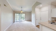 This single-floor, 2-bedroom, 2-bathroom residence at 9301 Spectrum Dr offers a practical and comfortable layout across a well-utilized footprint. The open kitchen is a standout feature, equipped with white shaker-style cabinetry, granite-look countertops, a peninsula with a double sink, and a full suite of stainless steel appliances including a refrigerator, microwave, and range. Wood-look flooring runs through the kitchen and main areas, transitioning to plush carpet in the living spaces and bedrooms. The living room is bright and airy, highlighted by a ceiling fan, crown molding, and a sliding glass door that opens to an outdoor balcony with views of surrounding greenery. The primary bedroom is generously sized and includes a walk-in closet with wire shelving. The second bedroom features a ceiling fan and a window with natural light and outdoor views. Both bathrooms offer tub/shower combinations with white tile surrounds and chrome fixtures. A dedicated in-unit laundry room accommodates a full-size side-by-side washer and dryer with overhead wire shelving. A hallway connects the bedrooms and bathrooms, providing a clean, organized flow throughout the home. Neutral wall tones and consistent finishes lend a cohesive, move-in-ready ambiance.