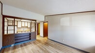 Located at 1056 Mindy Ln in Wooster, Ohio, this one-bedroom, two-bathroom home offers an efficient and well-organized single-floor layout. Light hardwood flooring runs throughout the space, complemented by neutral-toned walls, blue baseboards, and warm wood-toned trim that lend a cohesive character to each room.

The combined kitchen and living area forms the heart of the home. The kitchen is outfitted with ample white cabinetry trimmed in rich wood tones, a countertop with an integrated sink, a white electric range, and a full-size refrigerator. A skylight panel above the kitchen adds a bright, airy feel to the cooking space. An open built-in shelving unit with a wood-grain finish connects the kitchen to the living area, providing both storage and a natural visual divider.

The living room receives natural light through windows fitted with blinds, and features a textured ceiling throughout. The bedroom is a well-proportioned retreat with a sliding wood-panel closet, a window for natural light, and a flush-mount ceiling fixture.

Two bathrooms serve the home, one of which features a marble-patterned vanity countertop and a full tub-shower combination. A utility room rounds out the layout, adding practical storage and functional support. The front entry opens to a window view of the surrounding neighborhood streetscape.