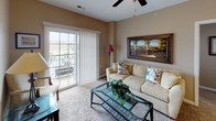 This single-floor residence offers a thoughtfully designed layout that balances comfort and functionality across its living spaces. The kitchen is a standout feature, equipped with rich cherry-toned cabinetry, granite countertops, stainless steel appliances including a refrigerator and microwave, and durable hardwood-style flooring. A granite-topped breakfast bar with pendant lighting provides additional seating and connects the kitchen to the adjacent living areas.

The dining area accommodates a full-sized table and chairs beneath a pendant light fixture, with double closet doors adding storage convenience nearby. The living room features plush carpeting, a ceiling fan, and sliding glass doors that open to a private balcony, filling the space with natural light.

The primary bedroom is generously sized, featuring carpet flooring, a ceiling fan, natural light from a window with blinds, and a large dresser with mirror. A secondary bedroom offers comfortable accommodations with twin beds, carpet flooring, and a window. The bathroom continues the granite and cherry wood aesthetic with a granite-topped vanity, a large mirror, and a shower-tub combination. Throughout the residence, warm beige walls and consistent finishes create a cohesive, welcoming ambiance.