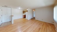 Located at 6411 W Bradley Rd in Milwaukee, WI, this single-floor unit offers a straightforward, functional layout highlighted by warm hardwood flooring that extends throughout the main living areas. The open living space is bright and airy, featuring white walls, standard ceiling height, and a large window dressed with vertical blinds that allows natural light to fill the room. A baseboard heating unit runs along the exterior wall, providing efficient warmth.

The kitchen is compact yet practical, featuring warm-toned wood cabinetry, a white refrigerator, a single-basin sink, and light tile flooring that transitions seamlessly from the hardwood in the adjacent living area. The cabinetry provides ample storage for everyday essentials.

A separate bedroom offers a clean, neutral space with white walls, hardwood floors, and its own doorway for privacy. The bathroom is outfitted with a full-sized soaking tub and shower combination, white square wall tiles, and classic white tile flooring accented with a blue tile border detail. A gold-toned towel bar adds a subtle decorative touch.

Overall, the unit presents a clean, move-in ready environment with a cohesive neutral palette and durable finishes throughout.