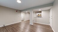 Located at 5604 Floyd St in Overland Park, Kansas, this single-floor unit offers a thoughtfully designed layout with a clean, modern aesthetic. The open living area is anchored by durable wood-look flooring and neutral gray walls, creating a bright and versatile space. A structural column adds architectural interest while subtly defining the transition between the living area and the kitchen pass-through. Natural light filters in through vertical blinds in the living room, enhancing the airy feel of the space.

The kitchen is well-equipped with white shaker-style cabinetry, dark granite-style countertops, and a full suite of stainless steel appliances, including a range, dishwasher, and refrigerator. A pass-through window connects the kitchen to the living area, improving sightlines and flow throughout the unit.

The bedrooms feature plush wall-to-wall carpeting and ceiling fans, offering a comfortable and quiet retreat. Each room includes a closet and ample wall space. The bathroom is finished with wood-look flooring, a full tub-shower combination, and a clean white vanity, maintaining the consistent modern style found throughout the unit. Overall, the space presents a cohesive, move-in-ready interior with practical finishes and a neutral palette.