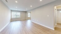 This two-story home in Lancaster, PA offers a thoughtfully designed layout with three bedrooms, two full bathrooms, and two living areas spread across two well-proportioned floors. The main level features a bright, galley-style kitchen outfitted with stainless steel appliances — including a gas range, built-in microwave, dishwasher, and full-size refrigerator — complemented by white shaker cabinetry, stone-look countertops, and light hardwood-style flooring. The kitchen opens to an adjacent living area filled with natural light from large windows. A dedicated utility room provides added convenience on this level. The main living room impresses with vaulted-style ceilings, recessed lighting, and an open staircase with sleek black metal railings leading to the upper floor. Upstairs, the three bedrooms are carpeted for comfort, each featuring ceiling fans and ample closet space with bifold doors. The primary bedroom offers generous proportions. The two bathrooms are finished with large-format neutral tile — one featuring a walk-in glass shower, the other a soaking tub with shower combo and chrome fixtures. Neutral gray tones, clean white trim, and consistent hardwood-style flooring throughout the main level create a cohesive, modern aesthetic across the entire home.
