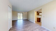 Located at 1548 Hunters Lake Dr E in Cuyahoga Falls, Ohio, this single-floor, two-bedroom, one-bathroom home offers a well-organized layout with consistent wood-look flooring throughout. The living room serves as the heart of the home, featuring a sliding glass door that fills the space with natural light and provides outdoor access. An open passageway connects the living area to the galley-style kitchen, which is equipped with dark wood cabinetry, white appliances including an electric range, microwave, refrigerator, and dishwasher, along with a stainless steel sink and ample counter space. The primary bedroom is a generously sized retreat featuring two large windows with views of surrounding greenery, providing plenty of natural light. It also includes a dedicated walk-in closet outfitted with wire shelving and hanging rods for organized storage. The second bedroom is a comfortable, well-lit room with its own window and neutral tones that complement the rest of the home. The full bathroom features a combined tub and shower, a wood-vanity with a light countertop, and neutral wall tones. Warm beige walls and clean white trim are consistent throughout, contributing to a bright and cohesive overall ambiance.