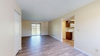 Located at 1548 Hunters Lake Dr E in Cuyahoga Falls, Ohio, this single-floor, two-bedroom, one-bathroom home offers a well-organized layout with consistent wood-look flooring throughout. The living room serves as the heart of the home, featuring a sliding glass door that fills the space with natural light and provides outdoor access. An open passageway connects the living area to the galley-style kitchen, which is equipped with dark wood cabinetry, white appliances including an electric range, microwave, refrigerator, and dishwasher, along with a stainless steel sink and ample counter space. The primary bedroom is a generously sized retreat featuring two large windows with views of surrounding greenery, providing plenty of natural light. It also includes a dedicated walk-in closet outfitted with wire shelving and hanging rods for organized storage. The second bedroom is a comfortable, well-lit room with its own window and neutral tones that complement the rest of the home. The full bathroom features a combined tub and shower, a wood-vanity with a light countertop, and neutral wall tones. Warm beige walls and clean white trim are consistent throughout, contributing to a bright and cohesive overall ambiance.