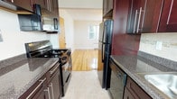 Located at 210 Crystal Lake Ave in Haddonfield, NJ, Unit 206A is a well-appointed single-floor residence featuring a thoughtfully designed layout with multiple bright, generously sized rooms. Gleaming hardwood floors flow throughout the living, dining, and bedroom areas, reflecting natural light that pours in through numerous double-pane windows fitted with blinds. Each room is equipped with a classic radiator heating system and ceiling fans, ensuring year-round comfort.

The galley-style kitchen is a standout feature, showcasing rich dark wood cabinetry with sleek silver hardware, granite countertops, a neutral tile backsplash, and a full suite of black appliances including a gas range, built-in microwave, dishwasher, and refrigerator. The kitchen transitions seamlessly into the living and dining areas, which offer an open, airy feel enhanced by natural light from surrounding windows.

The bedrooms are well-sized, each featuring hardwood floors, ceiling fans, and ample natural light through multiple windows. The bathroom is clean and functional, offering a dark wood vanity with a framed mirror, tile flooring, and a glass-door shower enclosure. A dedicated dining area with a pendant light fixture adds a defined sense of purpose to the floor plan. This unit combines classic character with modern updates in the heart of Haddonfield.