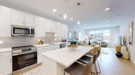 This thoughtfully designed 1-bedroom, 1-bathroom residence offers a cohesive, modern interior across a single level. The open-concept kitchen and living area serves as the heart of the home, where crisp white shaker cabinetry, a tile backsplash, and stainless steel appliances — including a refrigerator, range, microwave, and dishwasher — define a highly functional kitchen. A large center island with quartz countertops and seating for multiple guests doubles as a dining space, illuminated by sleek pendant lighting overhead. The living area flows seamlessly from the kitchen, featuring light hardwood flooring, large windows that invite abundant natural light, and access to an outdoor area, offering views of the surrounding neighborhood. The bedroom is a serene retreat with a generous window, ample natural light, and a ceiling fan, providing a calm and restful ambiance. A dedicated walk-in closet offers built-in shelving and hanging rods for organized storage. The full bathroom is clean and contemporary, featuring a glass-enclosed soaking tub, an extended double vanity with white cabinetry, and light wood-tone flooring. A dedicated entrance and additional closet complete this well-structured, move-in-ready residence.
