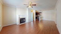 This single-floor residence offers a thoughtfully designed layout that balances open communal spaces with comfortable private quarters. The living room serves as the heart of the home, showcasing warm hardwood flooring, crown molding, a ceiling fan, and a classic fireplace with a white surround — an inviting focal point for the space. Natural light pours in through large windows, offering pleasant views of the surrounding greenery.

The living area flows seamlessly into a dedicated dining space, defined by hardwood floors and pendant lighting from the adjacent kitchen. The kitchen is well-equipped with rich, dark cabinetry, granite countertops, a mosaic tile backsplash, and a full suite of stainless steel appliances including a gas range, built-in microwave, and a side-by-side refrigerator with an ice and water dispenser. A breakfast bar provides additional seating and connects the kitchen to the main living areas.

The bedrooms are carpeted and generously sized, each featuring ceiling fans and ample natural light. The primary bedroom includes direct access to an en-suite bathroom. Bathrooms throughout are finished with dark vanity cabinetry, granite countertops, hardwood-style flooring, and tiled soaking tub-shower combinations, offering a clean and functional aesthetic.
