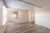 Located at 10891 Edgemere Blvd in El Paso, Texas, this single-floor unit offers a functional and straightforward layout throughout. The open living area is finished with wood-look laminate flooring that extends through most of the space, providing a cohesive and easy-to-maintain surface underfoot. A textured popcorn ceiling and neutral warm-toned walls create a simple, consistent aesthetic throughout.

The kitchen is positioned adjacent to the living area and features a pass-through counter that connects the two spaces. Gray cabinetry with ample upper and lower storage pairs with a tile mosaic backsplash, a gas range, and a sink with views into the living area, making the kitchen both practical and open.

The bedrooms are comfortably sized, each benefiting from natural light through horizontal-blind-covered windows that offer views of the surrounding greenery. One bedroom includes a ceiling fan for added comfort. The rooms provide a calm, neutral environment well-suited for a variety of uses.

The bathroom is well-appointed with a full tub-shower combination featuring floor-to-ceiling tile surround in a warm tan hue, a vanity with storage, and wood-look flooring that ties into the rest of the unit. A front entry door with a large window allows additional natural light into the living space, enhancing the overall brightness of the unit.