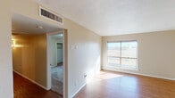 This single-story space is organized around a central hallway finished with wood-look flooring that connects the main living areas. The entry opens into a spacious living area bathed in natural light from a large sliding window that frames expansive open field views beyond. The flooring throughout the common areas and select rooms is a warm-toned wood-look laminate, while the bedrooms are finished with carpet.

The galley-style kitchen features white cabinetry, dark laminate countertops, a double-basin stainless steel sink, and wood-look flooring, providing a functional and organized cooking space. A full bathroom includes a tiled tub-surround in earthy tones, a white vanity with cabinet storage, and coordinating wood-look flooring.

The bedrooms offer a quiet retreat, each with carpeted floors, natural light from individual windows, and dedicated closet space. One bedroom features a ceiling fan and large window with views of the surrounding landscape, while another includes a reach-in closet with built-in shelving. Textured ceilings and neutral wall tones are consistent throughout, contributing to a cohesive and understated ambiance across the entire space.