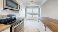Located at 333 Rue Riverside in Saint-Lambert, this thoughtfully designed 3-bedroom, 2-bathroom residence offers a bright and functional layout across a single floor. Light wood flooring flows consistently throughout the space, lending a warm and cohesive feel to every room.

The open-concept kitchen and living area serves as the heart of the home. The kitchen is outfitted with white cabinetry, wood-tone countertops, a stainless steel appliance suite including a range, microwave, and refrigerator, a subway tile backsplash, and a central island. Large windows fill the kitchen with natural light and frame expansive outdoor views, extending to a private balcony accessible from the living area.

The living room is generously sized, featuring floor-to-ceiling windows that invite abundant natural light and provide sweeping views of the surrounding area. Each of the three bedrooms is bright and well-proportioned, with large windows offering outdoor views and ample closet space — the unit includes four closets in total. The primary bedroom is notably spacious.

The two bathrooms are finished with clean grey subway tiling. One features a full soaking tub with overhead shower, while the second includes a sleek glass-enclosed walk-in shower. A hallway connects the rooms, completing this well-organized and move-in-ready residence.