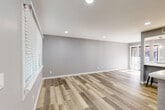 Located at 2220 E 7th St in Charlotte's vibrant Plaza Midwood neighborhood, this thoughtfully updated 1-bedroom, 1-bathroom unit offers a clean, modern aesthetic throughout. The open-concept kitchen and living area is anchored by a white brick fireplace and large windows dressed with white blinds, filling the space with natural light. Recessed lighting and light-toned wood-look flooring run throughout, lending a cohesive, contemporary feel.

The kitchen is well-appointed with white shaker cabinetry, bright white countertops, stainless steel appliances including a refrigerator, range, microwave, and dishwasher, plus a deep undermount sink with a modern pull-down faucet. A peninsula provides additional counter space and casual dining potential.

The bedroom is comfortably sized, featuring a ceiling fan, a generous closet, and a window that brings in natural light. In-unit stacked laundry is conveniently accessible from the bedroom hallway.

The bathroom is elegantly finished with large-format marble-look tile on both the floors and tub surround, paired with a white vanity and chrome fixtures for a crisp, polished look.

Additional highlights include a private balcony, a utility room, and two closets offering practical storage. The unit's neutral gray palette and modern updates create a clean, move-in-ready environment.