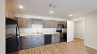 This single-story, 2-bedroom, 2-bathroom residence in Selmer, Tennessee offers a clean, modern aesthetic throughout. Wood-style plank flooring flows consistently across all rooms, lending a cohesive and contemporary feel to the entire space.

The living room is bright and inviting, featuring a set of glass French doors that flood the room with natural light and provide views of the surrounding community. The kitchen is well-equipped with rich, dark cabinetry extending to the ceiling, light granite-style countertops, a double-basin sink, and black appliances including a range, microwave, and dishwasher. Recessed lighting highlights the functional, galley-style layout.

The primary bedroom is generously sized and includes a ceiling fan, a natural light-filled window, and a walk-in closet outfitted with multi-tiered wire shelving for organized storage. The second bedroom features a standard reach-in closet. Both bathrooms are finished with dark wood vanities, granite-style countertops, and tiled tub-shower combinations.

A dedicated laundry room includes a full-size washer and dryer with overhead wire shelving. The walk-in closet provides additional storage with wrap-around wire shelving on multiple walls. Neutral wall tones and clean white trim throughout create a bright, move-in-ready atmosphere.