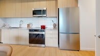 Located at 2108 16th Avenue West in Vancouver's sought-after Kitsilano neighbourhood, this well-appointed one-bedroom, two-bathroom unit offers a thoughtfully designed layout across a single floor. Light-toned hardwood flooring flows throughout, creating a warm and cohesive aesthetic.

The open-concept kitchen is outfitted with flat-panel light wood cabinetry extending to the ceiling, a classic subway tile backsplash, and a full suite of stainless steel appliances including a bottom-freezer refrigerator, electric range with over-the-range microwave, and dishwasher. A glass-top dining table with leather chairs sits adjacent, making the space ideal for both everyday living and entertaining.

A dedicated office provides a quiet, functional workspace with direct sightlines to the living and dining areas. The bedroom is bright and inviting, framed by large windows on two walls that invite abundant natural light and leafy outdoor views. A closet provides practical storage.

Two well-finished bathrooms serve the unit: one features large-format white wall tiles, a soaker tub with shower combination, and a wood-accented vanity, while the second offers a sleek walk-in shower enclosed by floor-to-ceiling neutral stone-toned tiles. Both bathrooms maintain the unit's clean, modern character throughout.