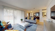 This single-floor residence offers a thoughtfully designed layout that balances comfort and functionality. The living room serves as the heart of the home, featuring light wood flooring, a large sliding glass door dressed with vertical blinds, and an outdoor view of a greenspace beyond. The room opens naturally toward a dining area, creating a connected, open-concept feel. Framed botanical artwork and a neutral color palette accented with navy and yellow tones lend a cohesive, contemporary style throughout.

The galley-style kitchen is well-equipped with stainless steel appliances, granite-look countertops, and track lighting overhead. Light wood flooring continues throughout, and a pass-through window adds a charming detail connecting the kitchen to an adjacent space.

Both bedrooms are comfortably sized and feature ceiling fans, wood-look flooring, and windows with blinds that allow for ample natural light. The primary bedroom includes a dresser with a wall mirror, while the second bedroom is similarly outfitted with matching nightstands and framed artwork. Both rooms maintain the home's consistent blue and yellow design theme.

Two bathrooms serve the residence, each with a shower/tub combination. One features a grey vanity with warm wood flooring, while the other is finished with neutral tones and decorative accents. The overall ambiance of the space is bright, clean, and move-in ready.