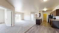 Located at 5652 26th St S in Fargo, ND, this well-appointed 3-bedroom, 2-bathroom unit offers a thoughtfully designed single-floor layout with generous living space throughout. The open-concept kitchen and living area serves as the heart of the home, featuring rich dark cabinetry, granite-style countertops, a breakfast bar peninsula, stainless steel appliances including a refrigerator, range, and microwave, and wood-look plank flooring. The living room extends toward a sliding glass door that opens to a private balcony, filling the space with natural light. Each of the three bedrooms is carpeted and finished with neutral tones, offering a comfortable and versatile atmosphere. The spacious primary bedroom includes a large walk-in closet with dual wire shelving systems for ample storage. The primary bathroom features a corner soaking tub accented with tile surround, while the second bathroom offers a full tub-shower combination. A dedicated in-unit laundry room with wood-look flooring and overhead shelving adds everyday convenience. Baseboard heating is present throughout, and the overall palette of warm neutrals creates a clean, move-in-ready environment.