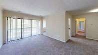 Located at 13801 Castle Blvd in Silver Spring, Maryland, this single-floor unit offers a well-organized layout designed for comfortable everyday living. The open living area is finished with neutral-toned carpet and crown molding, creating a clean, understated aesthetic. Large sliding glass doors with vertical blinds allow generous natural light to fill the space while providing access to an outdoor area and views of surrounding greenery.

The galley-style kitchen is outfitted with white cabinetry accented by chrome hardware, dark laminate countertops, wood-look vinyl flooring, and white appliances including a gas range and refrigerator. Crown molding carries through the kitchen, maintaining a consistent finish. A passthrough connects the kitchen to an adjacent carpeted area, adding functional flow to the layout.

The bedrooms are comfortably sized, each featuring plush carpet, neutral walls, and windows with vertical blinds that bring in natural light and outdoor views. The bathroom is finished with wood-look vinyl flooring, a tiled tub and shower surround, chrome fixtures, and clean white walls. Raised-panel interior doors are featured throughout, contributing to a cohesive and tidy overall presentation.