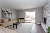 This single-floor residence at 1050 Locust St in Kansas City, KS, offers a well-organized layout designed for comfortable everyday living. The living area is finished with dark hardwood-style flooring and neutral gray walls, creating a clean, contemporary aesthetic. Two sofas anchor the space, complemented by a low-profile coffee table and accent lighting. A ceiling fan overhead adds both function and character. The living area flows seamlessly into a dedicated dining space, separated by a subtle beam detail, where a ceiling fan and wall art contribute to a cohesive atmosphere.

The kitchen is efficiently laid out in a U-shape, featuring white cabinetry with upper cabinets extending to the ceiling for ample storage, a dishwasher, electric range, and a full-size refrigerator, all set above warm hardwood-style flooring.

The bedroom is carpeted and generously proportioned, with a notable built-in window ledge running along a multi-pane window that invites natural light. The room connects directly to a walk-in closet offering shelving and hanging space, as well as an adjacent bathroom featuring a single vanity, textured walls, and a louvered window accent for privacy.