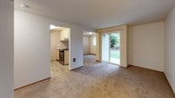 This single-floor residence offers a practical and straightforward layout designed for comfortable everyday living. The kitchen is efficiently arranged in a galley-style configuration, featuring light wood cabinetry with ample upper and lower storage, light-toned countertops, tile flooring, a built-in dishwasher, and an electric range — providing everything needed for daily meal preparation.

The living area is open and generously proportioned, finished with neutral wall-to-wall carpeting that extends into the adjoining spaces. A sliding glass door floods the room with natural light and provides direct access to an outdoor area overlooking greenery, creating a pleasant connection to the outside. The layout also reveals a passthrough view into the kitchen, supporting an open and connected feel between spaces.

The bedroom is a quiet, well-sized room with carpeted flooring, a window fitted with vertical blinds that allows natural light, and a textured ceiling. The full bathroom is accessed through a wood-paneled door and includes a single vanity with light wood cabinetry, a toilet, and a full tub-shower combination, all set on durable tile flooring. Throughout, the space maintains a clean, neutral palette.