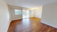 This well-appointed one-bedroom, one-bathroom residence in Kensington, MD offers a thoughtfully designed single-floor layout with hardwood-style flooring flowing throughout the entire space. The open living and dining area is bright and welcoming, featuring a sliding glass door flanked by large windows that flood the space with natural light and provide pleasant outdoor views. A pendant light fixture serves as a focal point in the dining area, adding a warm finishing touch. The modern kitchen is outfitted with crisp white shaker cabinetry, light quartz countertops, a subway tile backsplash, a center island for additional prep space, and a full suite of stainless steel appliances including a range, microwave, dishwasher, and refrigerator. The spacious bedroom offers a window for natural light, a ceiling light fixture, and direct access to two closets — one of which is a walk-in — providing ample storage. The bathroom features a clean, contemporary shower with a sliding glass enclosure and brushed gold fixtures. Clean white walls and neutral tones throughout the space create a bright, move-in-ready atmosphere that is both functional and inviting.