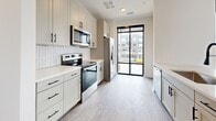 Located at 2314 Berryhill Rd in Charlotte, NC, this contemporary 2-bedroom, 2-bathroom residence offers a thoughtfully designed single-level layout with modern finishes throughout. Light gray luxury vinyl plank flooring runs continuously through the space, complementing the crisp white walls and creating a clean, cohesive aesthetic.

The open-concept kitchen is a standout feature, outfitted with white shaker cabinetry accented by matte black hardware, a herringbone-patterned tile backsplash, white quartz countertops, stainless steel appliances, and a matte black pull-down faucet. A glass door at the end of the kitchen invites abundant natural light and provides outdoor access.

The living area is defined by dramatic floor-to-ceiling black-framed windows that frame sweeping views of the surrounding Charlotte streetscape, flooding the room with natural light and lending an industrial-modern character to the space.

Both bedrooms are well-proportioned, featuring ceiling fans, crisp panel doors with black hardware, and large black-framed windows that continue the home's contemporary design language. The primary bedroom benefits from generous closet space.

The two bathrooms are elegantly appointed — one features a glass-enclosed walk-in shower with classic white subway tile and black-framed hardware, while the second offers a full soaking tub surrounded by floor-to-ceiling white subway tile, providing a clean and timeless finish.