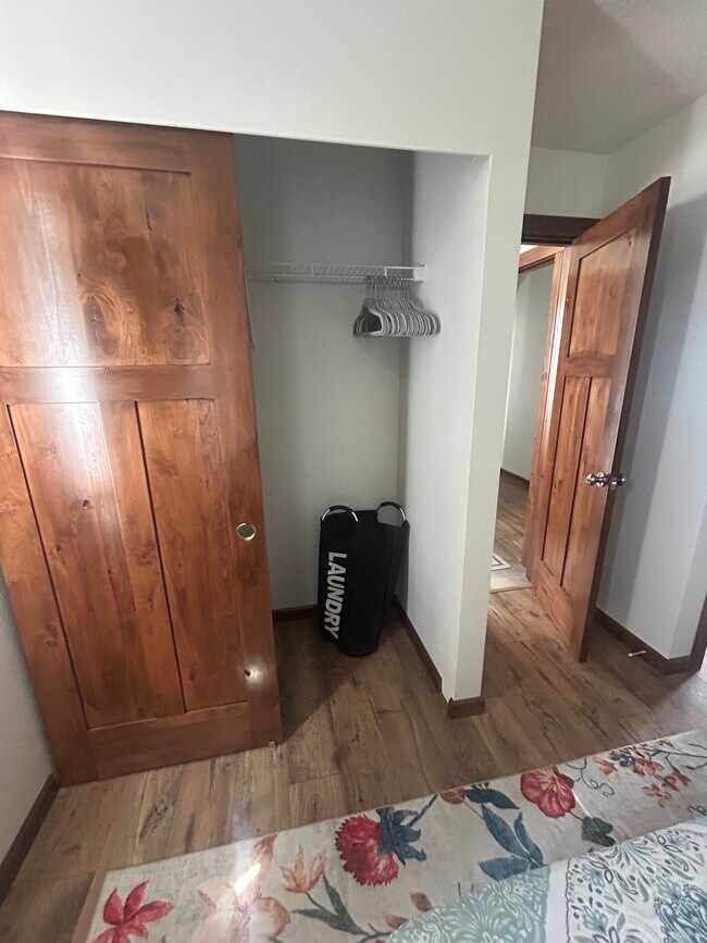 Armario en el dormitorio 1 con perchas, cómoda pequeña y cesto para ropa sucia. - 34558 Fry Rd SE