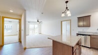 This well-appointed 3-bedroom, 2-bathroom residence in Mankato, Minnesota offers a thoughtfully designed single-floor layout ideal for comfortable everyday living. The open-concept kitchen and living area serves as the heart of the home, where warm wood-toned cabinetry, granite countertops, and a kitchen island with pendant lighting flow seamlessly into a bright, carpeted living room. Stainless steel appliances and light hardwood-style flooring complete the kitchen's modern, functional aesthetic. Sliding glass doors lead from the living room to a private balcony, inviting natural light deep into the space. The generously sized primary bedroom features multiple large windows that frame outdoor views and bathe the room in sunlight, complemented by a spacious walk-in closet with wire shelving. The additional bedrooms are well-proportioned with carpet flooring and ample natural light. Both bathrooms are finished with granite-topped vanities, rich dark cabinetry, and hardwood-style flooring. A dedicated in-unit laundry room with full-size washer and dryer adds everyday convenience. Throughout, the residence maintains a clean, neutral palette with warm trim accents, ceiling fans, and consistent finishes that create a bright, cohesive living environment.