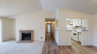 This 3-bedroom, 2-bathroom unit at Trrravista in Tacoma, WA offers a well-designed single-floor layout across a comfortable footprint. The living room is a standout space, featuring dramatic vaulted ceilings and a brick wood-burning fireplace as its focal point. A sliding glass door floods the area with natural light and provides access to a private balcony. The living room transitions seamlessly between plush carpet and wood-look flooring that extends into the adjoining areas. The galley-style kitchen is efficiently arranged with white cabinetry, granite-style countertops, and white appliances including a range and refrigerator. A pass-through opening connects the kitchen to the dining area, enhancing the open feel. A pantry provides additional storage. The three bedrooms are carpeted and offer a quiet retreat, with the primary bedroom providing a generous amount of space. Sliding wood-paneled closet doors add a classic touch. The two bathrooms feature wood-look flooring, vanities with granite-style countertops, and a shower/tub combination. A dedicated closet and in-unit pantry round out the functional storage options throughout this well-appointed Tacoma residence.