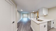 Located at Sixth Street in Cambridge, MA, this thoughtfully designed 2-bedroom, 1-bathroom residence offers a functional and modern living environment across a single floor. The open-concept layout seamlessly connects the kitchen, dining, and living areas, maximizing the efficient use of space.

The kitchen is a standout feature, equipped with stainless steel appliances including a gas range, microwave, and refrigerator. White cabinetry provides ample storage, while the peninsula with a white quartz countertop and matte black faucet over a stainless steel sink serves as both a prep area and casual dining space. Durable wood-look flooring runs throughout the main living areas, adding warmth to the contemporary design.

The living room benefits from a large window that frames views of the surrounding Cambridge streetscape, filling the space with natural light. Both bedrooms feature light wood-tone flooring and generous windows that bring in additional daylight and outdoor views of the vibrant neighborhood. The primary bedroom offers a comfortable footprint well-suited for furnishing.

The bathroom is clean and well-appointed, featuring a white vanity with dark hardware, a large mirror with overhead lighting, a full-size soaking tub with shower, and neutral tile flooring. Recessed lighting throughout the residence contributes to a bright, polished ambiance.