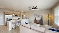 This single-story home offers a thoughtfully designed layout with 3 bedrooms and 3 bathrooms. The open-concept living and kitchen area serves as the heart of the home, featuring light wood-look flooring, recessed lighting, and a ceiling fan with integrated light. The kitchen is outfitted with light wood cabinetry, white quartz countertops, stainless steel appliances including a refrigerator, microwave, and range, and a peninsula with bar seating—ideal for casual dining. The living area receives abundant natural light through large windows fitted with blinds and is equipped with a wall-mounted HVAC unit for year-round comfort. Bedrooms feature plush carpeting, ceiling fans, and windows that bring in natural light. Each bedroom is supported by its own bathroom, one of which includes a full soaking tub and shower combination with black hardware accents. Three closets provide generous storage throughout, including a spacious walk-in closet with multi-level shelving and hanging rods. A dedicated laundry area houses a full-size Samsung washer and dryer set with overhead shelving. The attached garage offers a clean concrete floor, an electrical panel, and automatic opener, completing this well-equipped home.