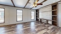 Located at 606 S Park St in Ogden, Kansas, this single-story, 3-bedroom, 2-bathroom home offers a well-designed layout with a warm, rustic aesthetic throughout. The open-concept kitchen and living area serves as the heart of the home, showcasing rich hardwood-style plank flooring, decorative dark wood ceiling beams, and a ceiling fan. The living area features shiplap accent walls and a built-in bench with open shelving, adding both character and functionality. The kitchen is well-appointed with gray shaker-style cabinetry, a center island with a gray countertop, a stainless steel range hood, and black appliances, complemented by ample counter space and a pantry for additional storage. The spacious primary bedroom includes multiple windows for natural light and a built-in shelving unit. The primary bathroom offers a dual-sink vanity with dark countertops, open shelving, and a soaking tub. Secondary bedrooms feature plush carpeting and natural light. A dedicated laundry room provides upper and lower cabinetry with a dark countertop. The second bathroom includes a tub-shower combo. A patio and closet round out this thoughtfully arranged home.