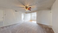 This single-story, 3-bedroom, 1-bathroom home in Austin, TX offers a functional and comfortable layout across a well-utilized floor plan. The living area features plush wall-to-wall carpeting, a ceiling fan with light fixture, and a textured popcorn ceiling. It flows openly into a dining or sitting area distinguished by classic wainscoting panel detailing along the lower walls and a grid-pane window that draws in natural light. Hardwood flooring anchors this brighter secondary space, creating a pleasant contrast with the carpeted main area. The kitchen is efficiently designed with white cabinetry, granite-look countertops, a gas range, and a dishwasher, all set over warm hardwood floors. The spacious primary bedroom includes its own ceiling fan and carpeted flooring, providing a generous and private retreat. Two walk-in closets offer ample built-in shelving and hanging rods for organized storage. The bathroom features a full tiled tub-shower combination with chrome fixtures and clean white tile surround. A connecting hallway ties all rooms together for easy navigation throughout the home. This residence provides a practical and comfortable living environment in a convenient Austin location.