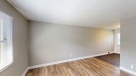 Located on Conway Ave in Charlotte, NC, this single-floor, 2-bedroom, 1-bathroom home offers a straightforward and functional layout designed for comfortable everyday living. The living room serves as the central gathering space, featuring light wood-tone laminate flooring, neutral gray walls, and a window that invites natural light and views of the surrounding neighborhood. Clean white baseboards and trim provide a crisp contrast throughout.

Both bedrooms are carpeted in a warm beige tone and painted in soft gray hues, creating a calm and restful atmosphere. Each room benefits from natural light through windows with horizontal blinds, and six-panel white doors add a classic touch. The primary bedroom offers a comfortable footprint, well-suited for a standard bedroom arrangement. The second bedroom is similarly appointed with a window overlooking greenery outside.

The bathroom is finished in a clean, all-white palette, featuring a tub-and-shower combination with full tile surround, chrome fixtures, a rain-style showerhead, and a built-in shelf niche. A window above the tub allows for ventilation and natural light.

Overall, the home presents a clean, move-in ready aesthetic with consistent neutral finishes, practical flooring choices, and a cohesive design that suits a range of lifestyles.