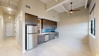 Located at 1140 E Market St in Akron, Ohio, this thoughtfully designed one-bedroom, one-bathroom unit offers a modern urban living experience with impressive architectural character. The open-concept main living area seamlessly combines the kitchen, dining, and living spaces beneath dramatically high ceilings with exposed structural beams, creating an airy, loft-inspired ambiance. The kitchen is a standout feature, equipped with a full suite of stainless steel appliances including a refrigerator, dishwasher, microwave, and range, complemented by rich dark wood cabinetry, light countertops, and a vibrant blue subway tile backsplash that adds a bold design accent. Light-toned flooring runs throughout, enhancing the brightness of the space. The bedroom is generously sized and features soaring ceilings with a structural column detail, lending an industrial-chic feel. It includes access to two closets, providing ample storage. The bathroom is finished with large-format gray tile, a glass-enclosed walk-in shower, a double-sink vanity with white countertops, and clean, contemporary fixtures. A dedicated utility room and hallway round out the layout, while the overall neutral color palette and modern finishes create a polished, move-in-ready environment.