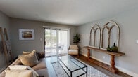 Located at 1188 Mallard Creek Rd in Louisville, Kentucky, this single-floor residence offers a well-designed layout with a cohesive, neutral aesthetic throughout. The living room is an inviting, light-filled space anchored by hardwood-style flooring, a textured ceiling, and a large sliding glass door fitted with vertical blinds that opens to an outdoor patio, allowing natural light to pour in and providing seamless indoor-outdoor connectivity. Decorative arched mirror panels add a distinctive architectural touch to the room. The adjacent dining area features track lighting overhead, hardwood-style floors, and a window that contributes additional natural light, creating a bright and functional space. The kitchen is well-appointed with white shaker cabinetry, white countertops, a subway tile backsplash, and a full suite of stainless steel appliances including a range, microwave, dishwasher, and refrigerator, all set atop light hardwood-style flooring. Two bedrooms each feature plush carpeting or hardwood-style floors, ceiling fans, and windows that invite natural light. The two bathrooms are finished with wood-look flooring, white vanities with ample storage, and mirrors. One bathroom includes a shower-tub combination, while the other features a standalone vanity layout, both reflecting clean, updated finishes throughout.